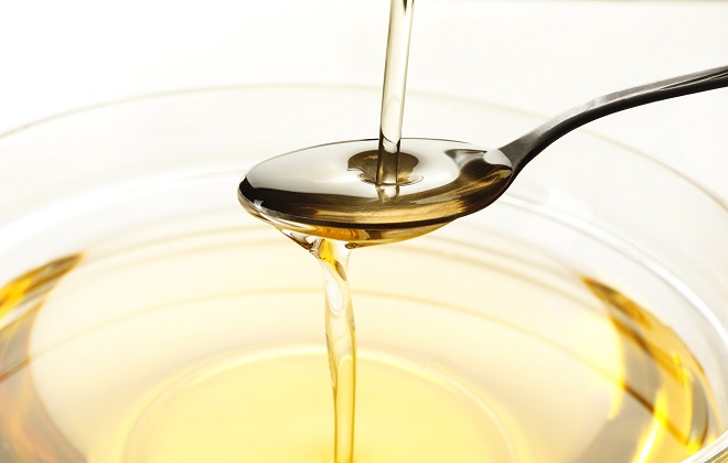 Pouring cooking oil into spoon and glass bowl, closeup